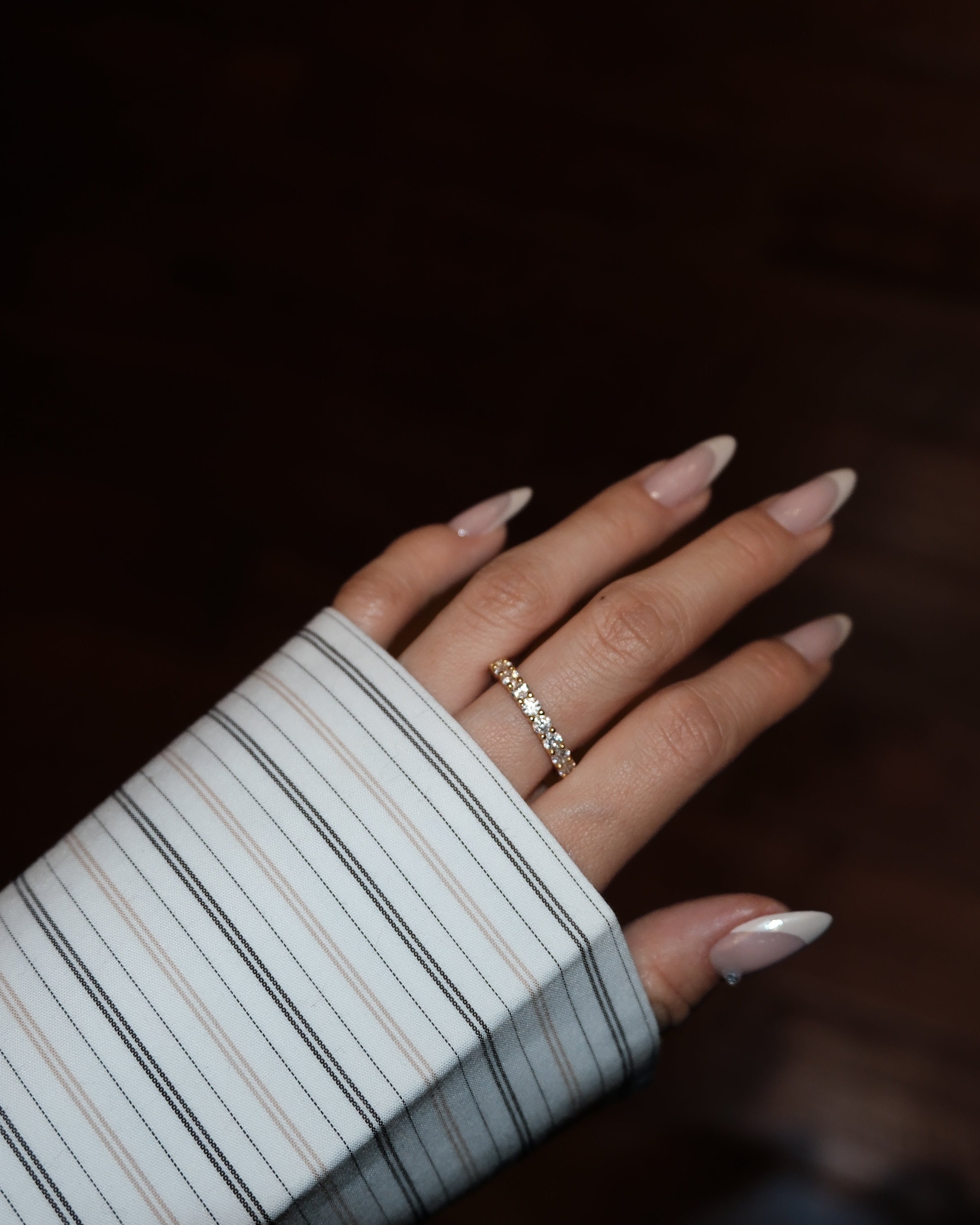 Hand with LUME dues gold ring on a dark background