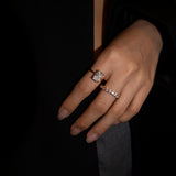Close-up of a hand wearing the elodie ring and dues ring both in gold on a dark background