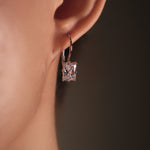 Close-up of a diamond earring on an ear with a dark background